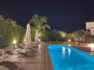 una piscina por la noche con sombrillas y sillas en Le Zarafe, en Caltabellotta