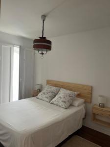 a bedroom with a white bed with two pillows at Apartamento RENACIMIENTO con garaje in Badajoz