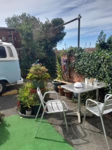 eine Terrasse mit einem Tisch, Stühlen und Pflanzen in der Unterkunft Janet Hale Studios, Garden Apartment in Glastonbury