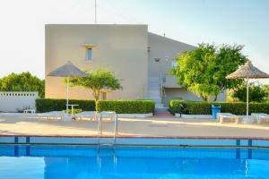 una piscina con sedie e ombrelloni di fronte a un edificio di Golden Dream Apartments a Hersonissos