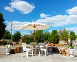 a table with an umbrella and two white chairs at Dom Na Ludowo w Brzeźnicy in Brzeźnica