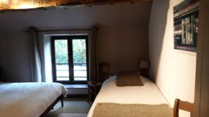 een slaapkamer met 2 bedden en een raam bij La Ferme du Couchant in Beauraing
