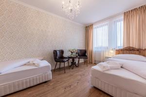 a bedroom with two beds and a table and a chandelier at Hotel Ondava in Stropkov