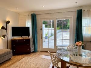 uma sala de estar com uma mesa de vidro e uma televisão em Relaxing 2 Bedroom Garden Cottage em Coleraine