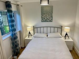 um quarto com uma cama branca e 2 candeeiros em Relaxing 2 Bedroom Garden Cottage em Coleraine