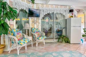 Zimmer mit Stühlen, einem TV und einem Kühlschrank in der Unterkunft Pams Mermaid House with Riverfront Yard and Lanai! in Weeki Wachee