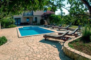 a swimming pool with chaise lounges next to a house at House /Villa Maja in Ližnjan