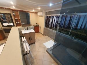 a bathroom with a sink and a glass shower at Bikkurim Inn in Nelspruit