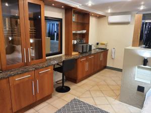 uma cozinha com armários de madeira, uma secretária e um frigorífico em Bikkurim Inn em Nelspruit