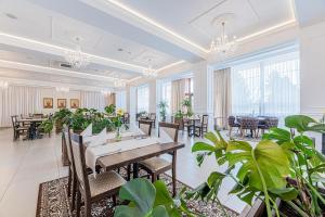 a dining room with tables and chairs and plants at Hotel Ondava in Stropkov