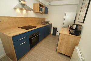 eine Küche mit blauen Schränken, einer Spüle und einem Kühlschrank in der Unterkunft Label OR appartement spacieux proximité pistes in Les Deux Alpes