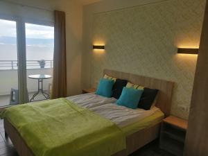 a bedroom with a bed with blue pillows and a balcony at Vila Vista Magica Radozda in Struga