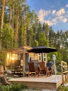 eine Hütte mit Stühlen und einem Sonnenschirm auf einem Deck in der Unterkunft HAIKANTIE 17 in Jyväskylä