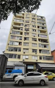 un edificio alto amarillo con coches estacionados frente a él en Sweet Studio Lapa, en Río de Janeiro