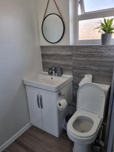a bathroom with a toilet and a sink and a mirror at Modern & Elegant Home w/ Netflix and Parking in Leeds