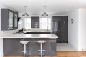 a kitchen with a large white counter and stools at Hampden Apartments - The Louis in Eton