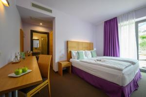 リーヴァ・デル・ガルダにあるActive & Family Hotel Gioiosaのベッド、デスク、テーブルが備わる客室です。