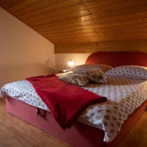 a bed in a bedroom with a wooden ceiling at Guest House Ema in Crni Lug