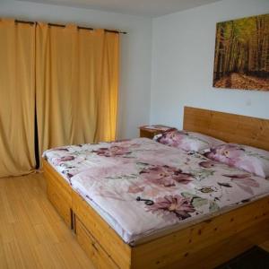 ein Schlafzimmer mit einem Holzbett mit rosa Blumen darauf in der Unterkunft Guest House Ema in Crni Lug