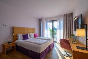 a hotel room with a bed and a desk and a window at Active & Family Hotel Gioiosa in Riva del Garda
