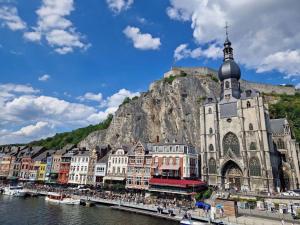 a large building with a church next to the water at Maison Saint Pierre in Dinant