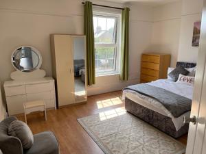 a bedroom with a bed and a mirror and a chair at Spacious 4-bed Holiday Home in the heart of Maidstone in Maidstone