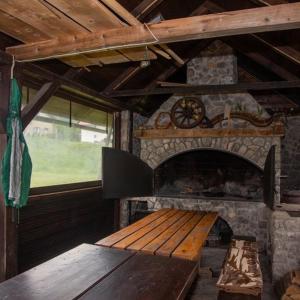 Habitación con chimenea de piedra y banco de madera. en Guest House Ema en Crni Lug