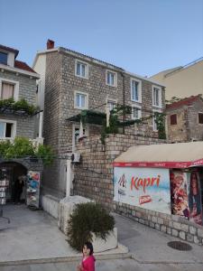 a girl walking down a street in front of a building at Apartmani More in Petrovac na Moru