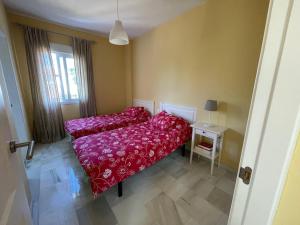 1 dormitorio con cama roja y mesa en Hochwertiges Haus in wunderschöner Golf Anlage am Meer, en Rota