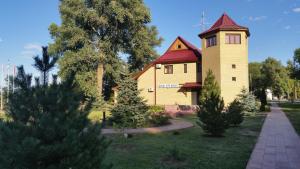 una casa amarilla con techo rojo y torre en Peresvet Park Hotel, en Verkhnyaya Akhtuba