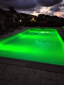 a green pool is lit up at night at Vila Emigrante in Capelas