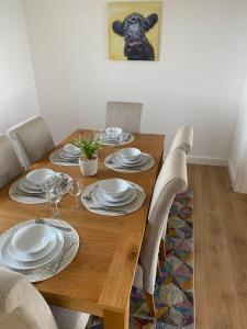 a wooden table with chairs and plates on it at Beachfront Penthouse, Largs in Largs