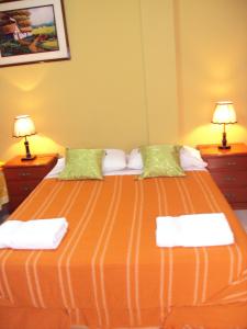 ein Schlafzimmer mit einem großen orangenen Bett mit zwei Lampen in der Unterkunft Nasca Lodge in Nazca