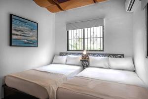 two beds in a room with two windows at Escape Apartment in Gazcue Close to Colonial Zone in Santo Domingo
