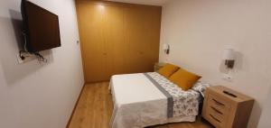 a small bedroom with a bed and a television at Apartamentos arcade in Arcade