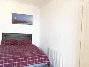 Beautiful 2 Bed Serviced Apartment in Dunbar في دنبار: غرفة نوم مع سرير وبطانية منقوشة