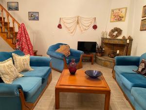 uma sala de estar com sofás azuis e uma mesa em Petra Maisonettes em Kariá