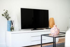 a tv on a white cabinet with a vase on a table at Lovely 2 bedroom apartment in Central Bristol in Bristol