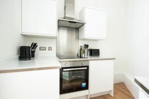 ブリストルにあるLovely 2 bedroom apartment in Central Bristolのキッチン(白いキャビネット、コンロ付)