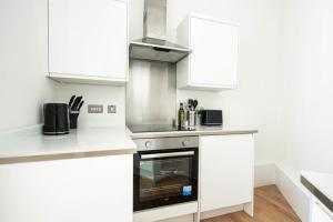 a kitchen with white cabinets and a stove top oven at Lovely 2 bedroom apartment in Central Bristol in Bristol