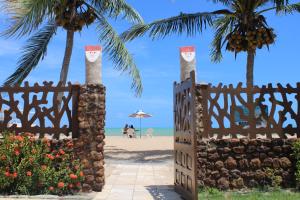 una puerta en la playa con palmeras en Pousada Coqueiro Verde, en Japaratinga