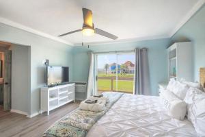 a bedroom with a bed with a ceiling fan and a window at Come Stay - and Sail Away - at this Lovely Canal Home in Freeport