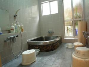 a bathroom with a bath tub and two toilets at Daiya Ryokan in Kyoto