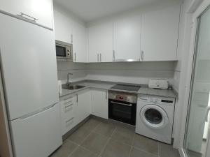 a white kitchen with a washing machine and a washer at Palmeiro in Jove