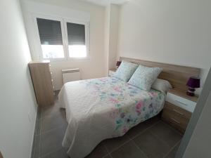 1 dormitorio con cama con colcha y almohadas de flores en Palmeiro, en Jove (Xove)