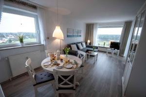 een woonkamer met een tafel en stoelen en een bank bij Frische-Brise-10-01 in Cuxhaven