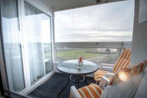 Zimmer mit einem Tisch und Stühlen sowie einem großen Fenster in der Unterkunft Frische Brise 10.01 in Cuxhaven