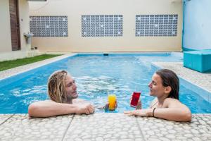 two people sitting in a swimming pool with drinks at Blue Coco in Keramas