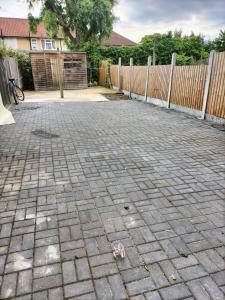 a brick driveway with a fence in a yard at Remaj Service Accommodation, Sleep 7 in Dagenham