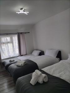 a bedroom with three beds and a ceiling fan at Remaj Service Accommodation, Sleep 7 in Dagenham